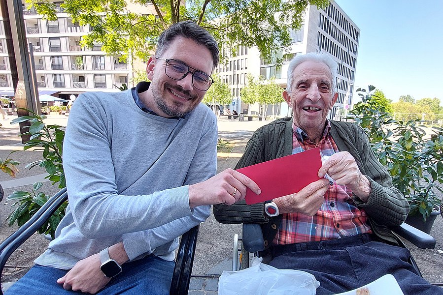 Herr Pegels übergibt den Geldumschlag.